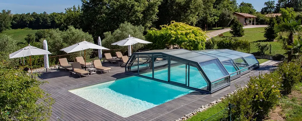 Abri de piscine haut adossé installé dans le jardin d’une villa dans le Var avec espace détente et terrasse bois