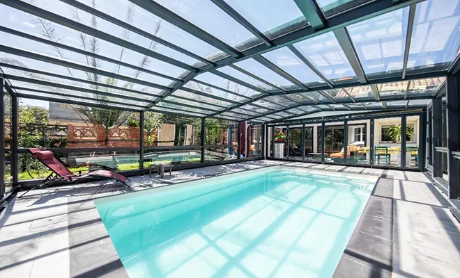 Grand abri de piscine haut lumineux installé dans le Var avec vaste espace de vie couvert autour du bassin